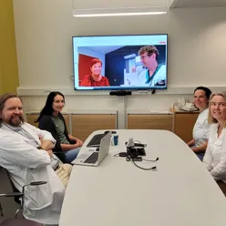 En gruppe mennesker som sitter rundt et bord med en bærbar datamaskin