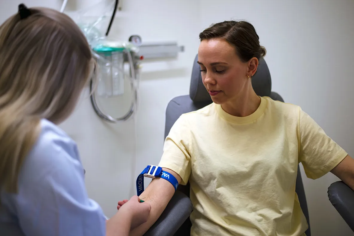En sykepleier som tar blodprøve på en kvinnelig pasient.