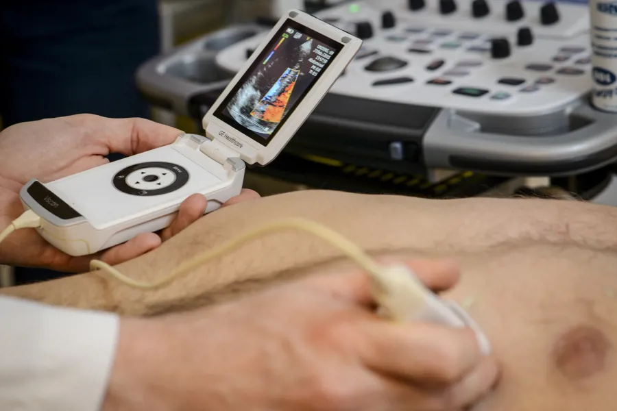Bildet viser en ultralydundersøkelse hvor legen bruker et håndholdt ultralydapparat. Foto
