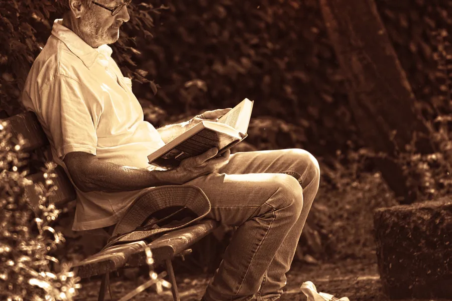 En mann som sitter i en stol og leser en bok