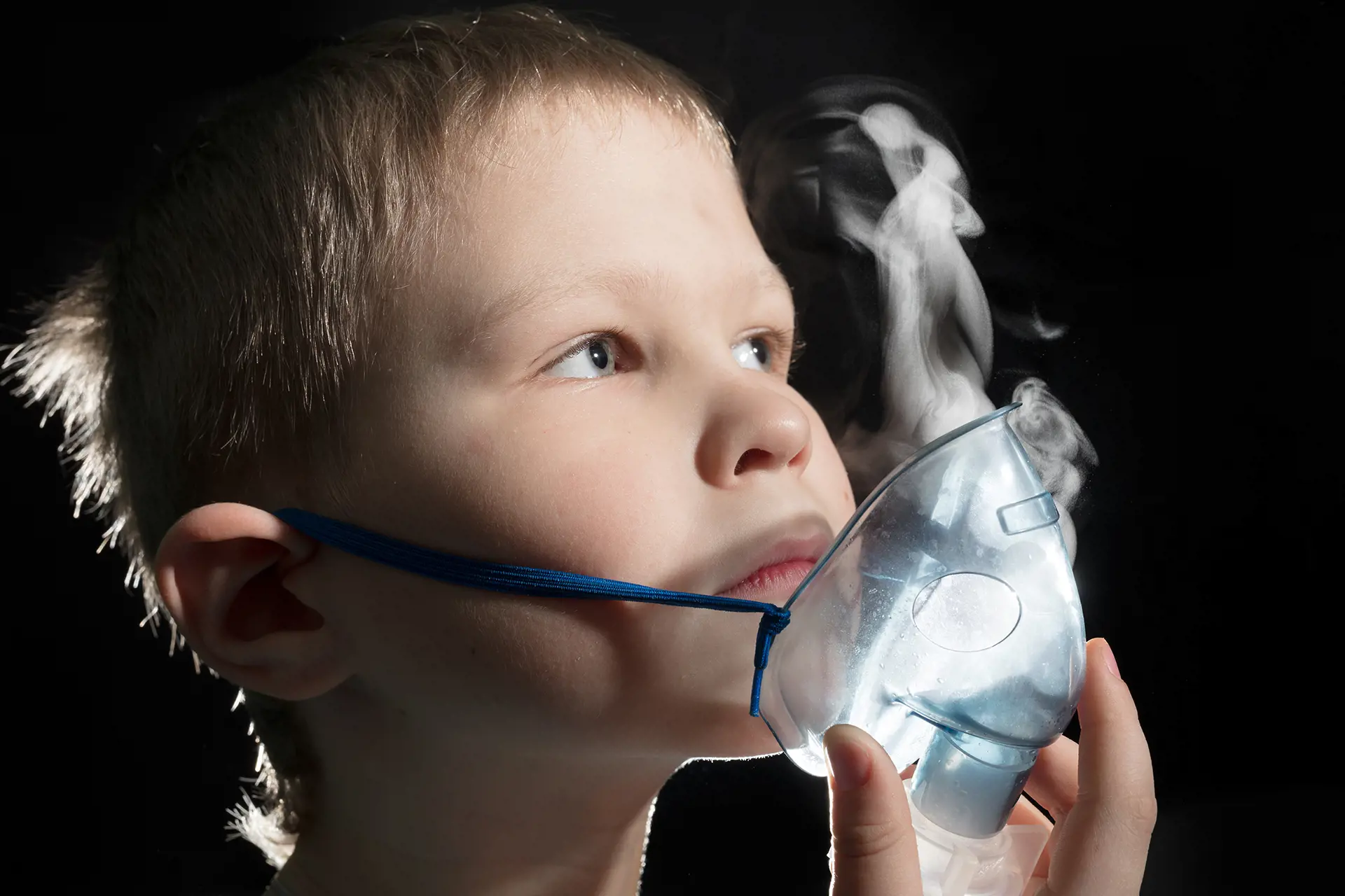 En liten gutt som holder en astmamaske foran munnen.