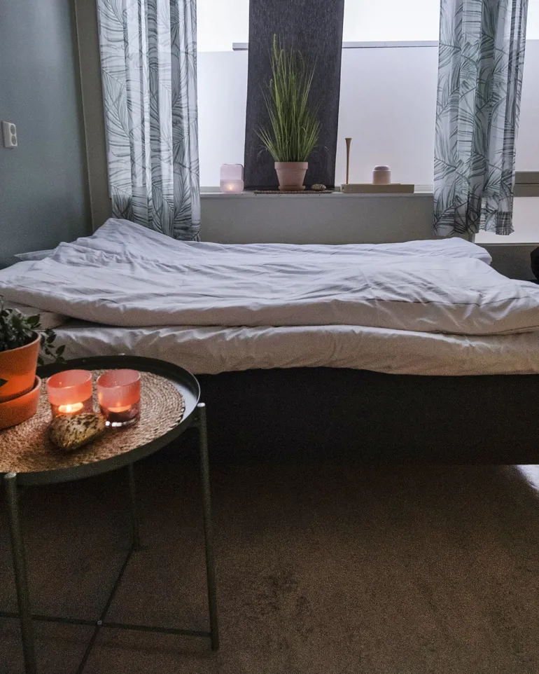 Foto fra rom m/seng og nattbord med stearinlys og plante
