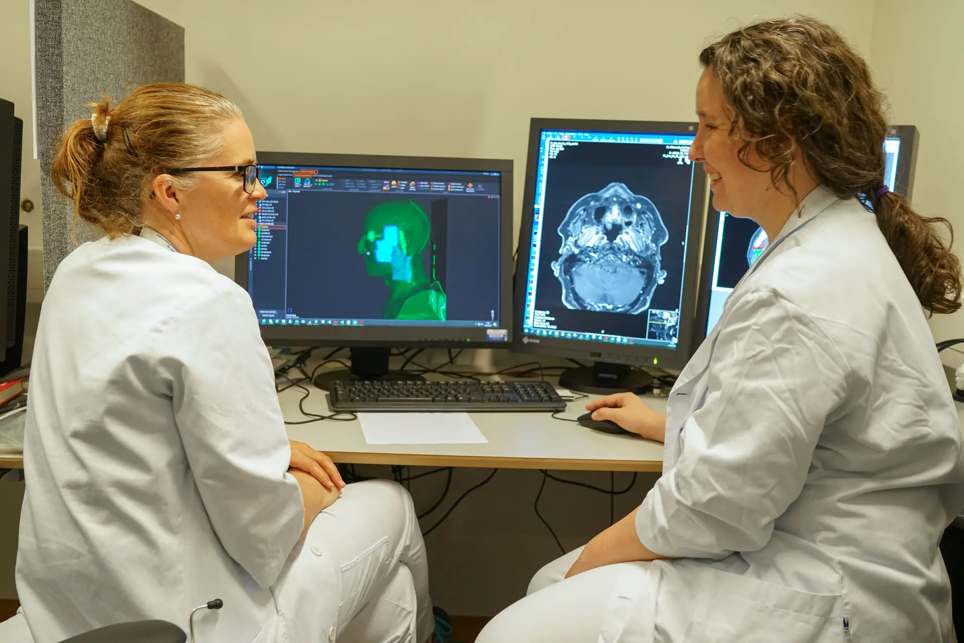To leger sitter og studerer røntgenbilder på to PC-skjermer.
