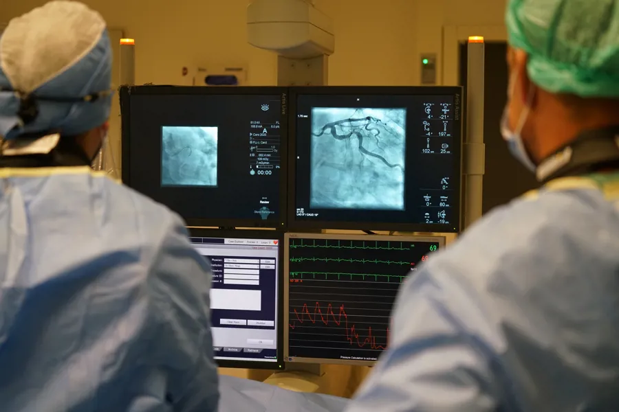 To leger som ser på to PC-skjermer som viser ultralydbilde av blodårer.