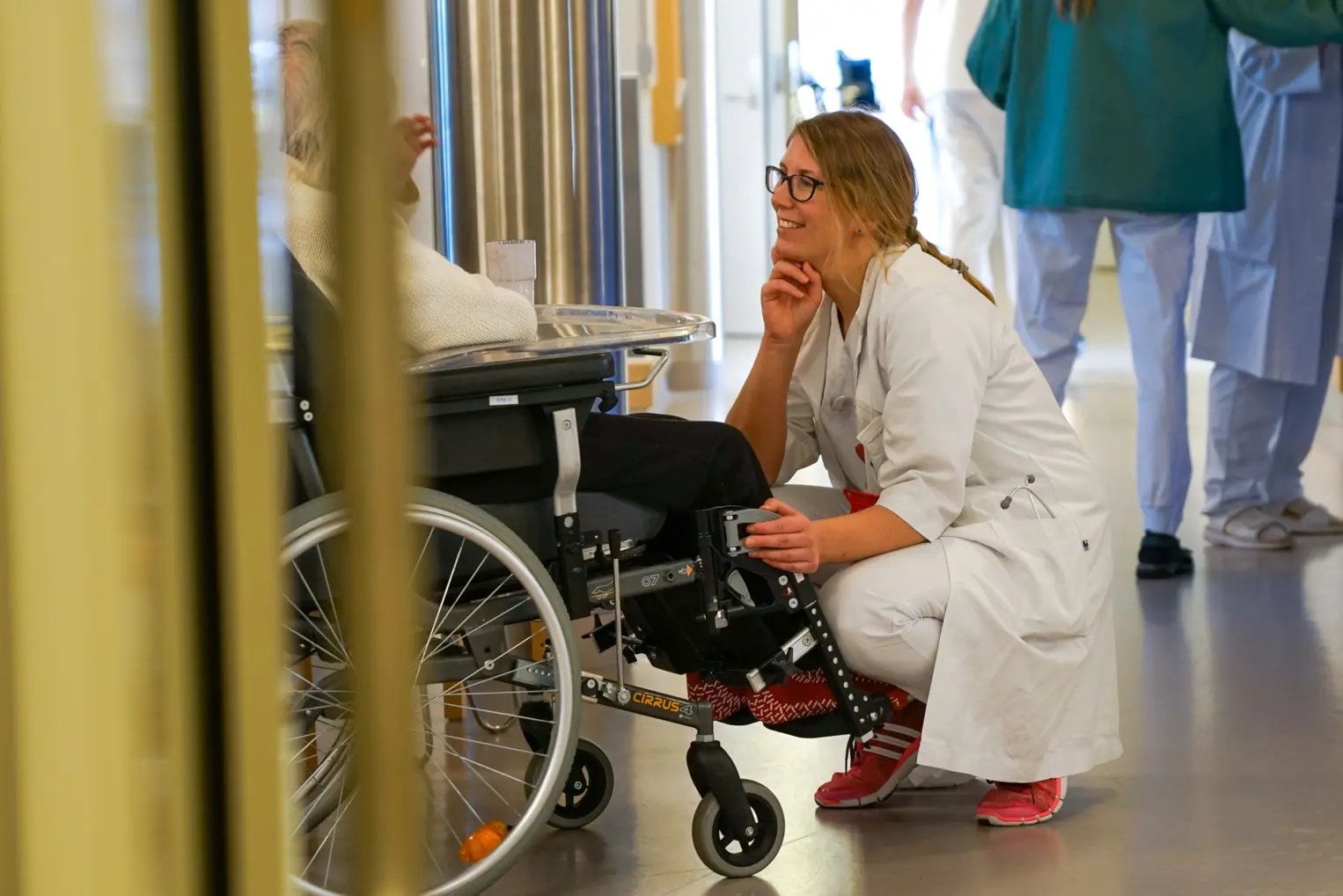 En sykepleier foran en person i rullestol